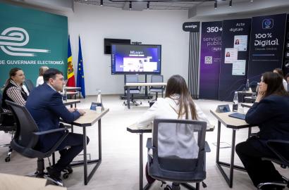 Ședință de lucru comună INAMP–AGE, cu participanții așezați în sală și o prezentare despre platforma MLearn afișată pe ecran, în contextul cooperării pentru digitalizarea formării profesionale în administrația publică.